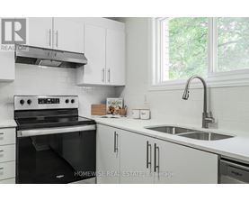 A white kitchen with a black stove and a sink.