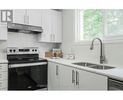 A white kitchen with a black stove and a sink.