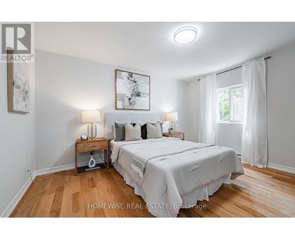 A bedroom with a large bed and a painting on the wall.