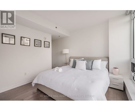 A bedroom with a large bed and pictures on the wall.