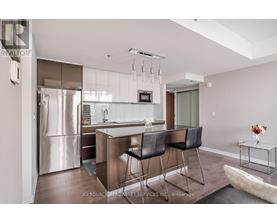 A modern kitchen with a refrigerator, sink, and bar stools.