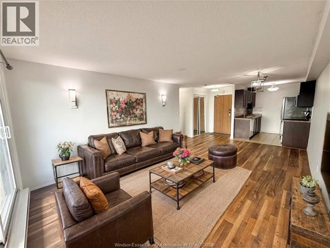 A living room with brown leather furniture and a wooden floor.
