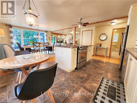 A kitchen with a table and chairs in the foreground and a refrigerator in the background.
