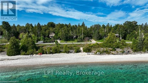 A beachfront property with a clear blue sky and a few trees in the background.