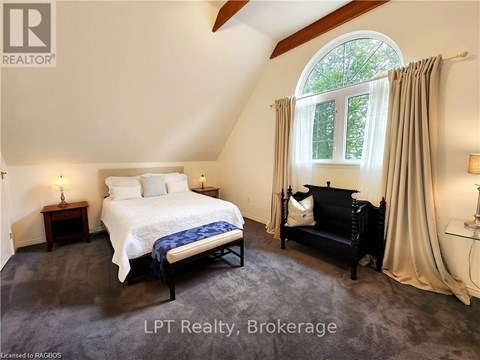 A bedroom with a large bed and a window with curtains.