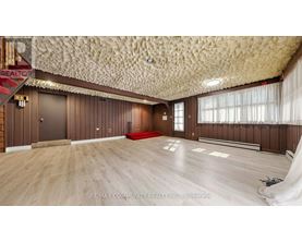 A spacious room with wooden floors and a textured ceiling.