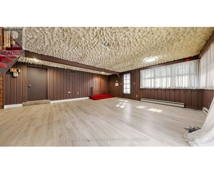 A spacious room with wooden floors and a textured ceiling.
