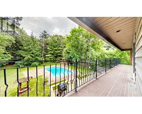 A pool surrounded by a black fence with a bench and a chair.