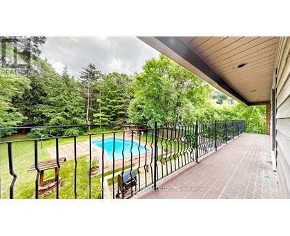 A pool surrounded by a black fence with a bench and a chair.