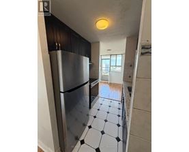 A kitchen with a black fridge and black and white tiles.