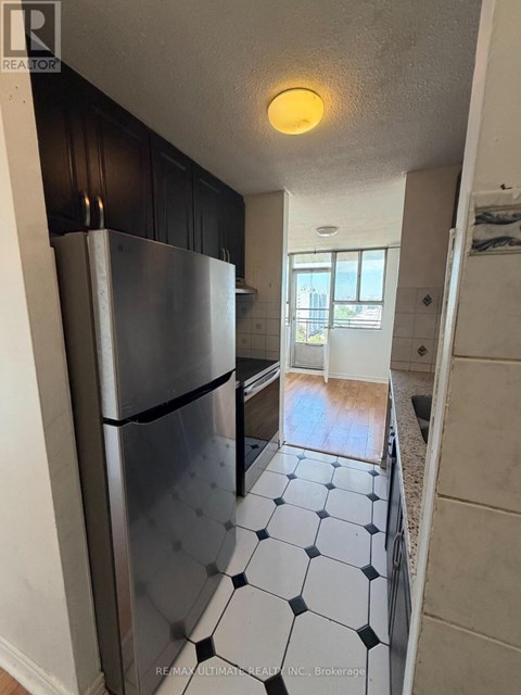 A kitchen with a black fridge and black and white tiles.
