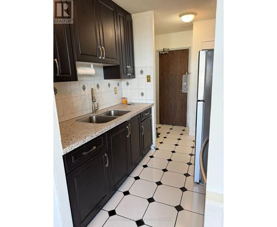 A kitchen with black cabinets and a checkered floor.