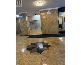 A hallway with a tile floor and a tile wall with a pattern.
