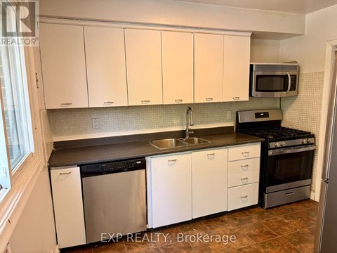 A kitchen with white cabinets and a black counter top.