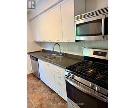 A kitchen with a stove, sink, and microwave.