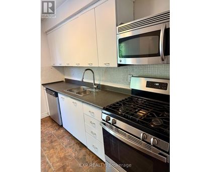 A kitchen with a stove, sink, and microwave.