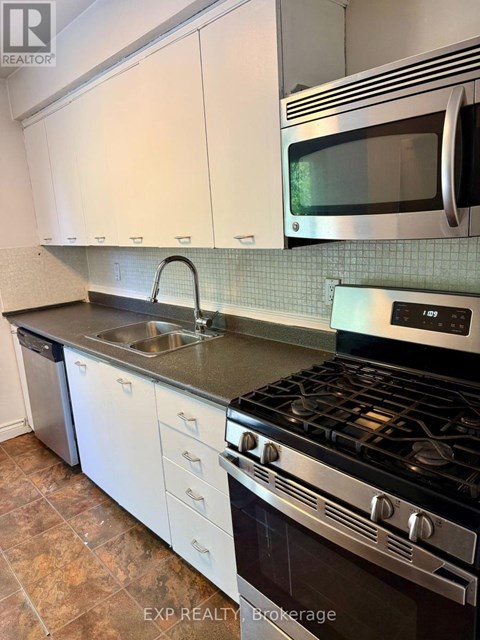 A kitchen with a stove, sink, and microwave.
