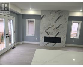 A marble fireplace in a room with grey walls and a window.