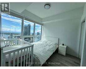 A bedroom with a large window overlooking a cityscape.