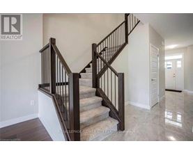 A staircase with a wooden handrail and a beige carpeted runner.