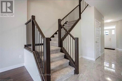 A staircase with a wooden handrail and a beige carpeted runner.