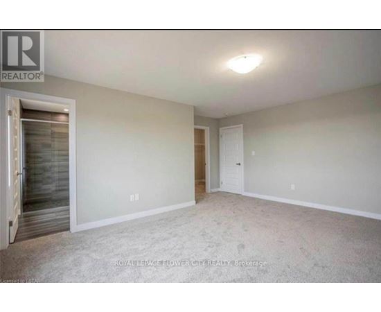 A spacious room with a door on the left and a carpeted floor.