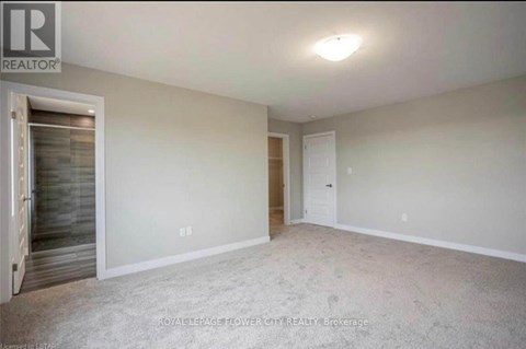 A spacious room with a door on the left and a carpeted floor.