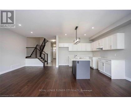 A spacious kitchen with white cabinets and a dark wood floor.