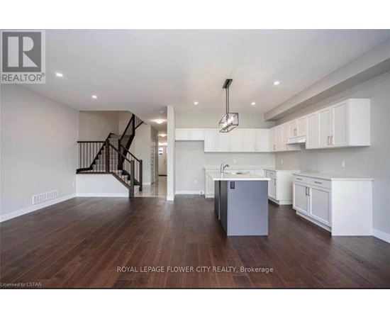 A spacious kitchen with white cabinets and a dark wood floor.