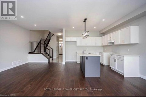 A spacious kitchen with white cabinets and a dark wood floor.