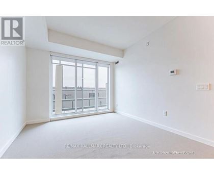 A white room with a window showing a view of a building.