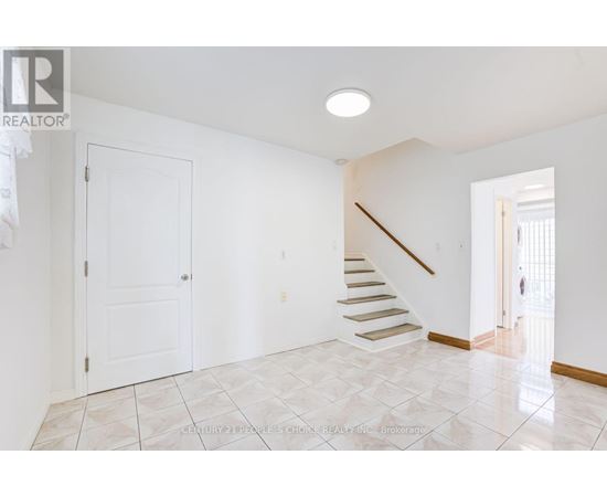 A spacious room with a staircase leading to the second floor.