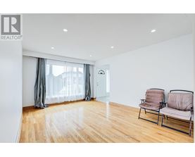 A living room with a wooden floor and two chairs.