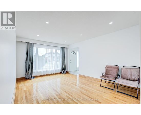A living room with a wooden floor and two chairs.