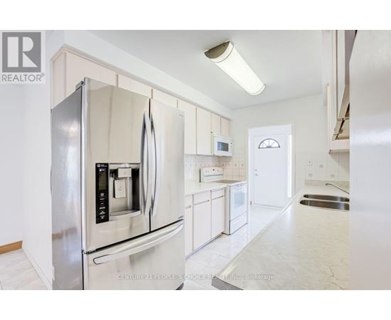 A modern kitchen with a stainless steel refrigerator and white cabinets.