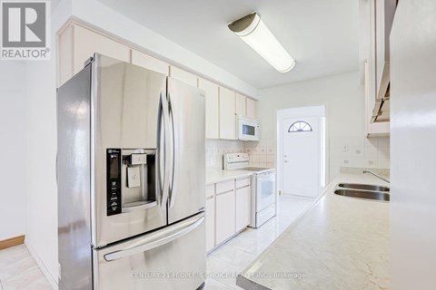 A modern kitchen with a stainless steel refrigerator and white cabinets.