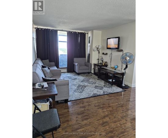 A living room with a television, a couch, a chair, and a table.