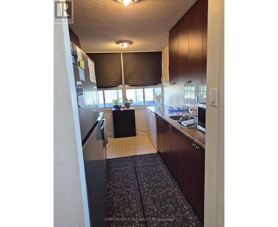 A kitchen with wooden cabinets and a black mat on the floor.