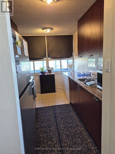 A kitchen with wooden cabinets and a black mat on the floor.