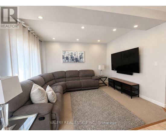 A living room with a grey sofa and a flat screen TV mounted on the wall.