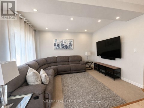 A living room with a grey sofa and a flat screen TV mounted on the wall.