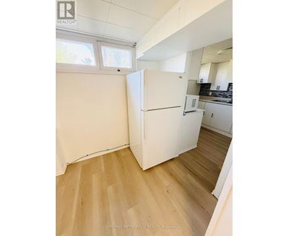 A white refrigerator in a kitchen with wooden floors.