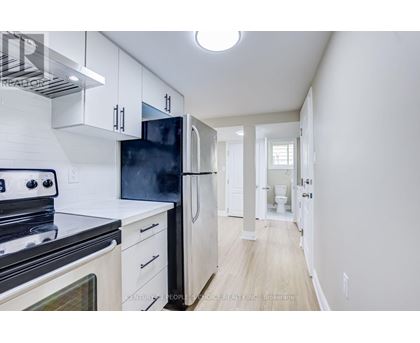A kitchen with white cabinets and a black fridge.