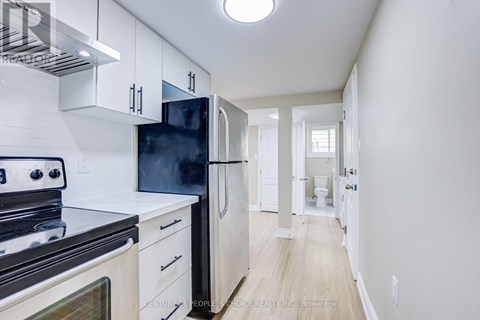 A kitchen with white cabinets and a black fridge.