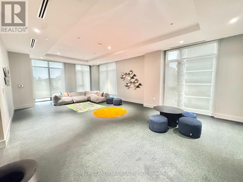 A spacious living room with a grey carpet and a large window.