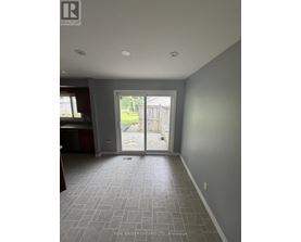 A room with grey tiled flooring and a sliding glass door leading to a backyard.