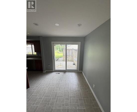 A room with grey tiled flooring and a sliding glass door leading to a backyard.