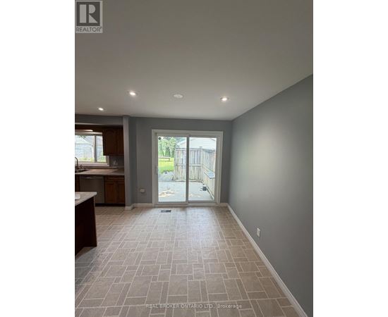 A spacious room with tile flooring and a sliding glass door leading to a balcony.