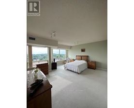A bedroom with a large bed and a dresser with a bowl of fruit on top.