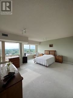 A bedroom with a large bed and a dresser with a bowl of fruit on top.